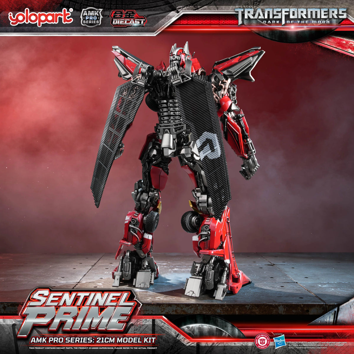 A rear-angle promotional image displaying the complex back structure of the model kit. It details how the segmented, cape-like red panels attach to the main die-cast spine structure, blending vehicle mode panel remnants with the robot mode's dense, layered cybernetic anatomy.